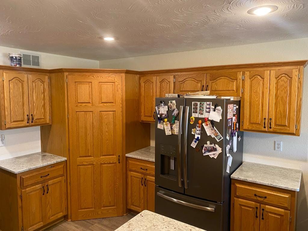 A kitchen with wooden cabinets and a black refrigerator.