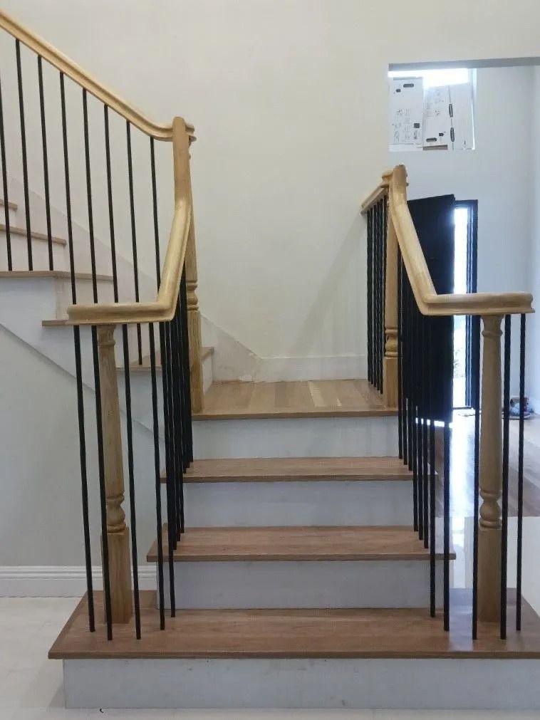 Wooden staircase with black railings, tan wood steps, and white risers.