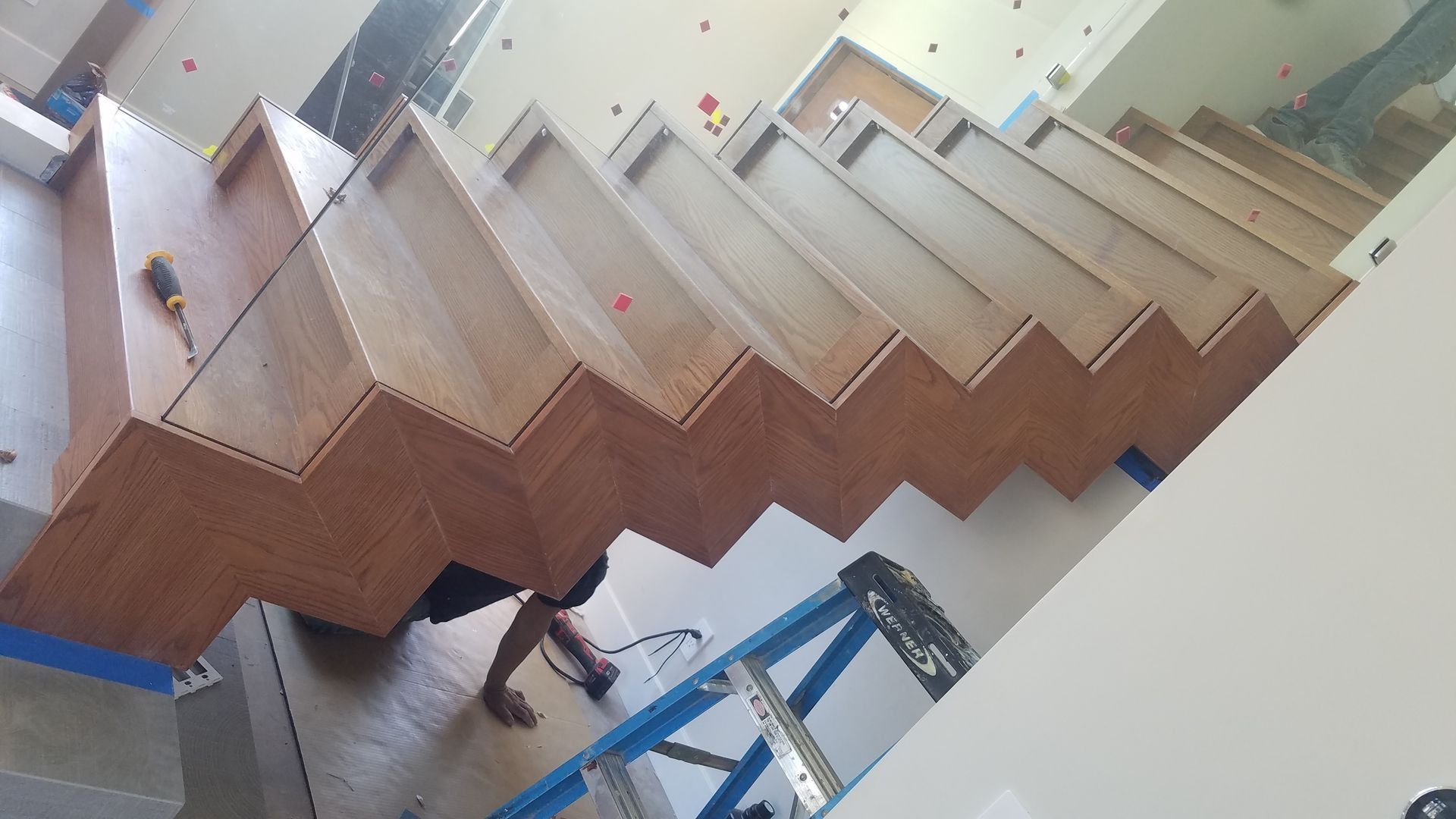 Person installing wooden stairs, using tools, indoors.