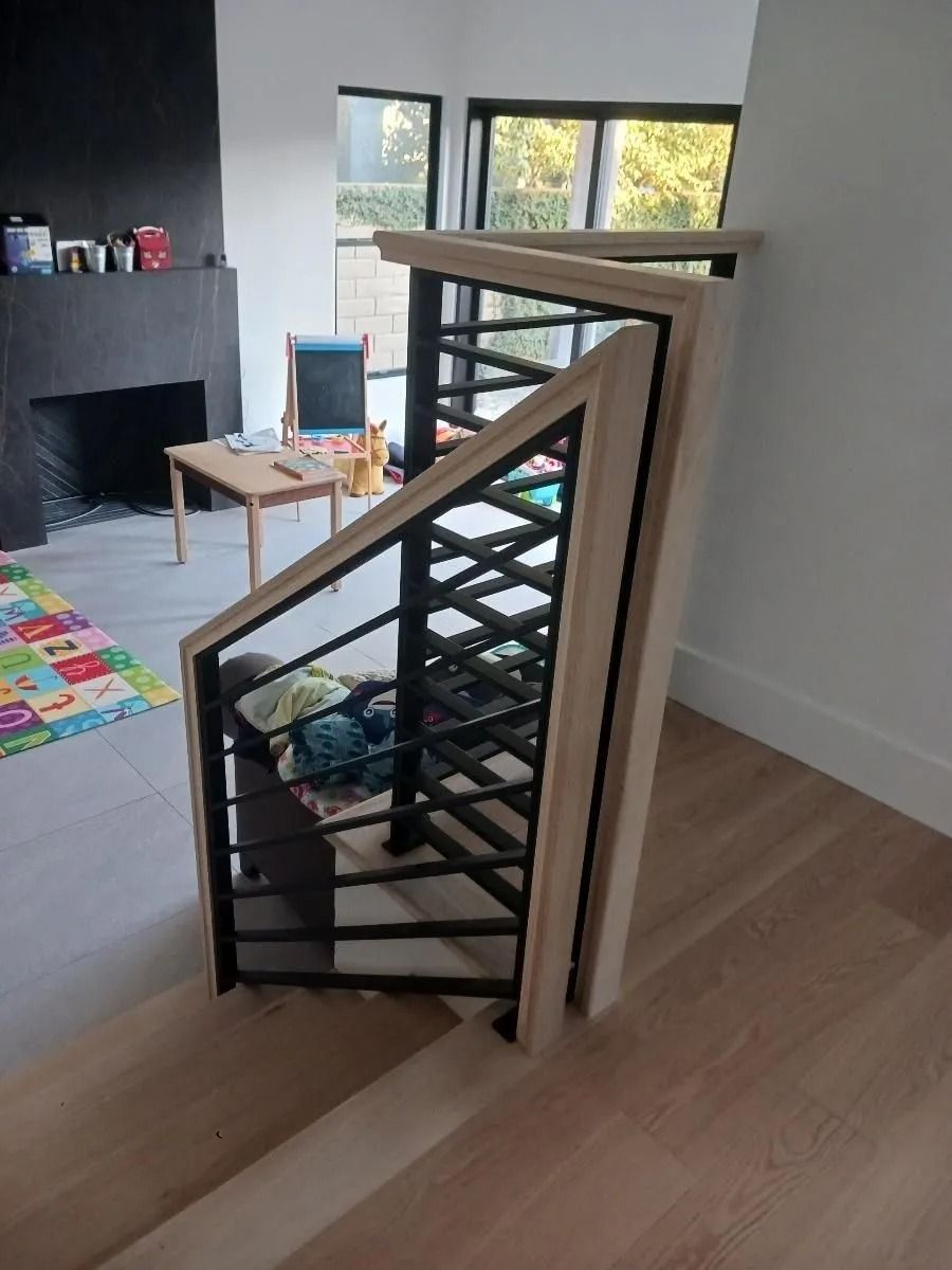 Staircase with black metal railing and light wood accents. Child's play area visible in background.