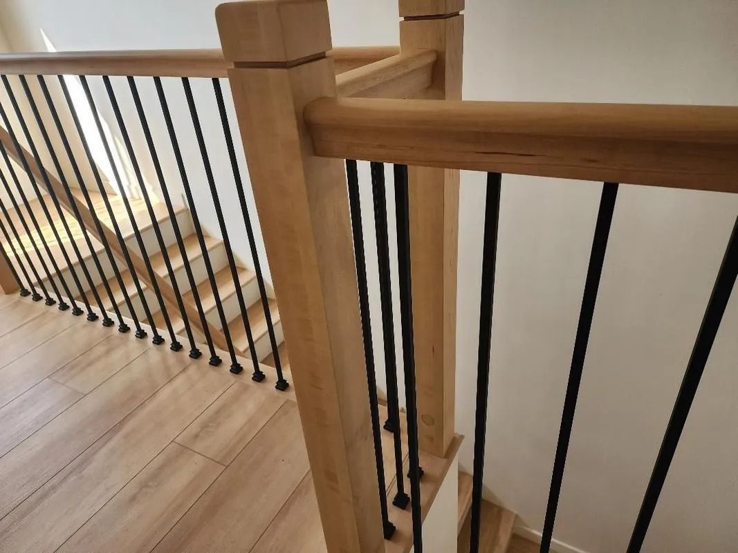 Wooden staircase with black metal spindles and light-colored flooring.