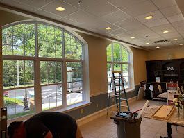 A man is working on a window in a room with a lot of windows.