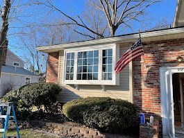 A house with a large window and an american flag hanging from the roof.