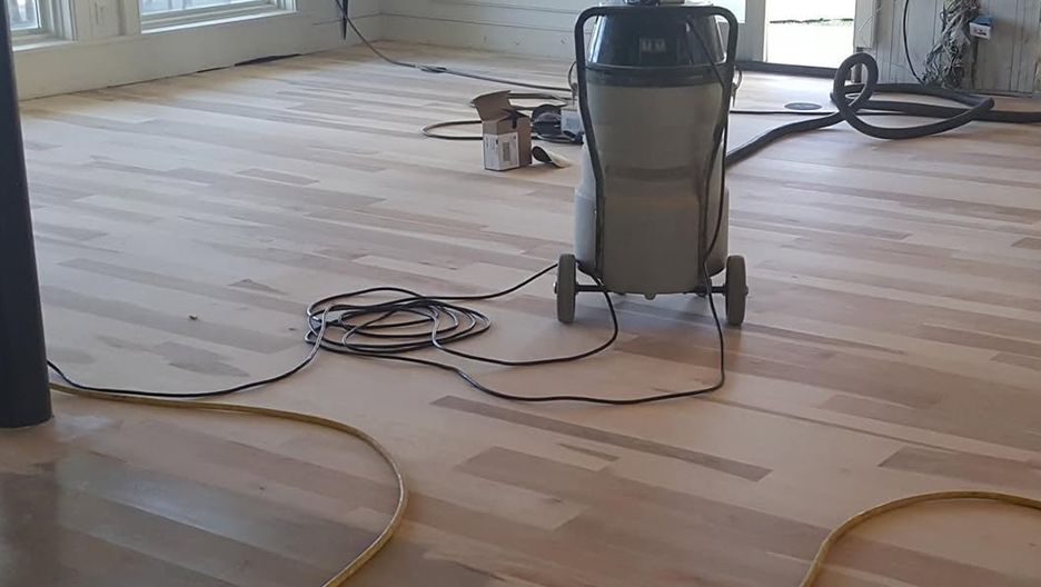A vacuum cleaner is sitting on a wooden floor in a room.