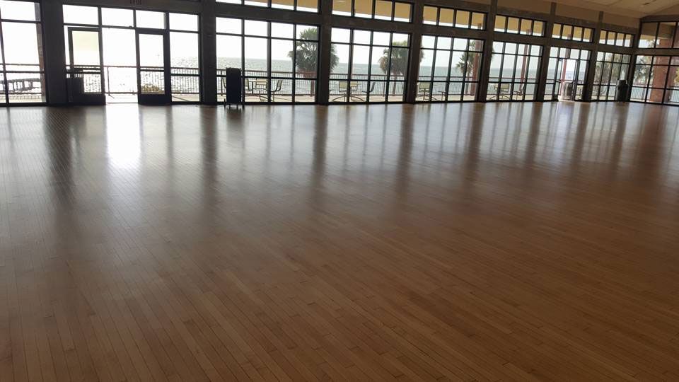A large empty room with a wooden floor and lots of windows.
