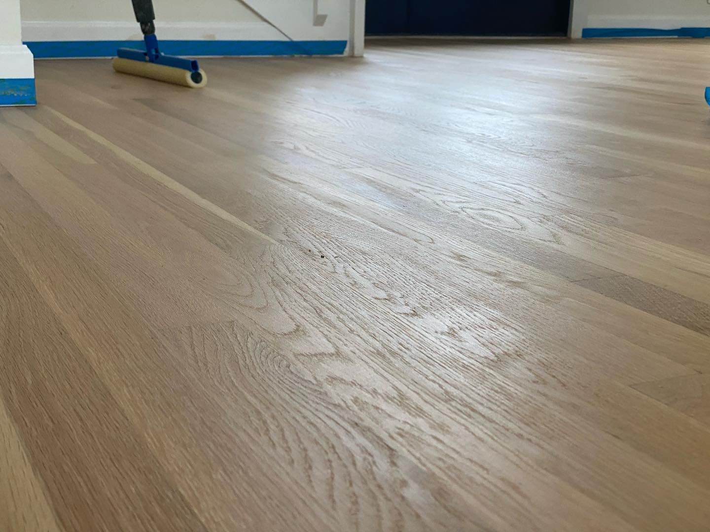 A person is cleaning a wooden floor with a mop.