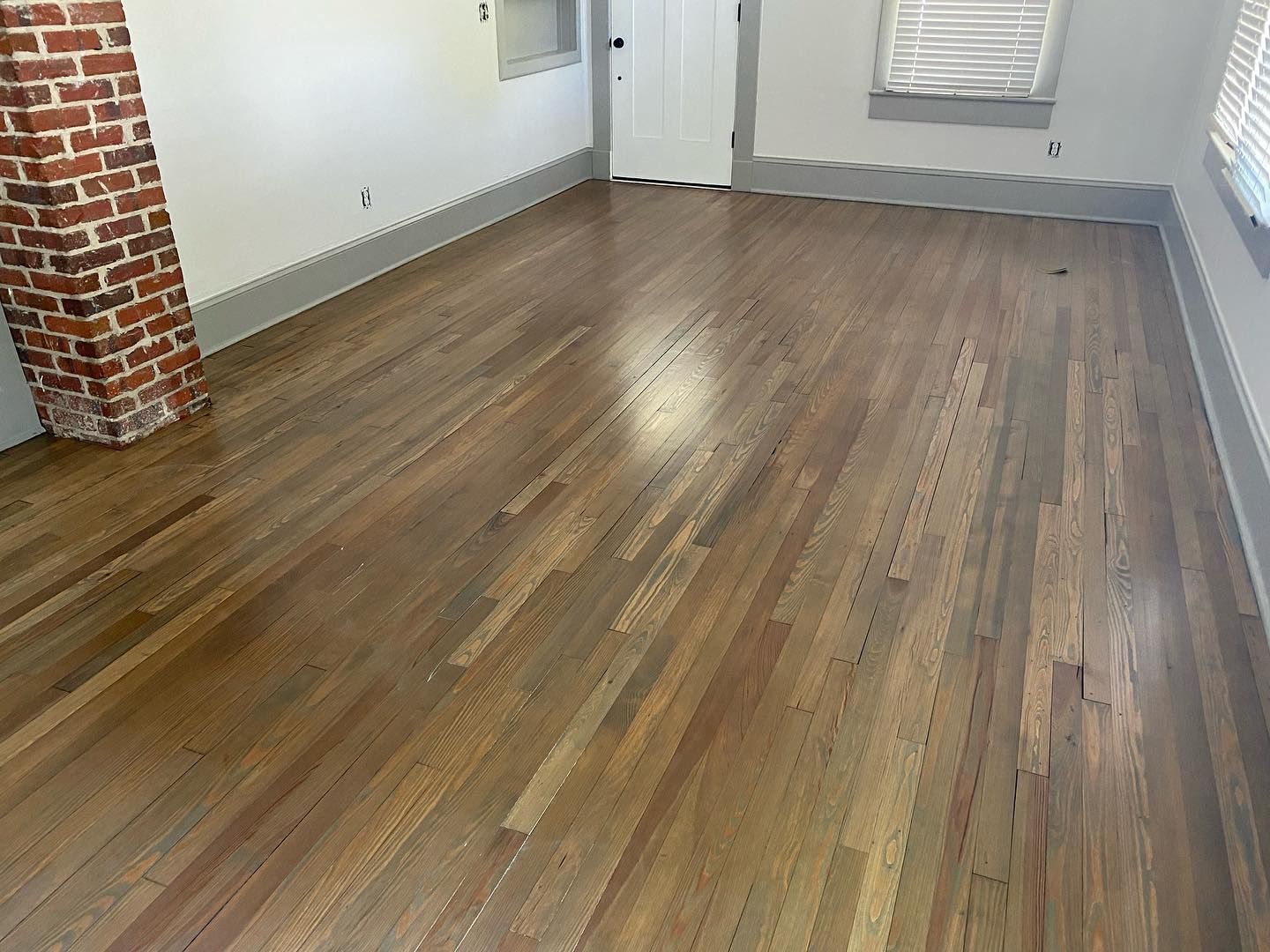 A living room with hardwood floors and a brick fireplace.