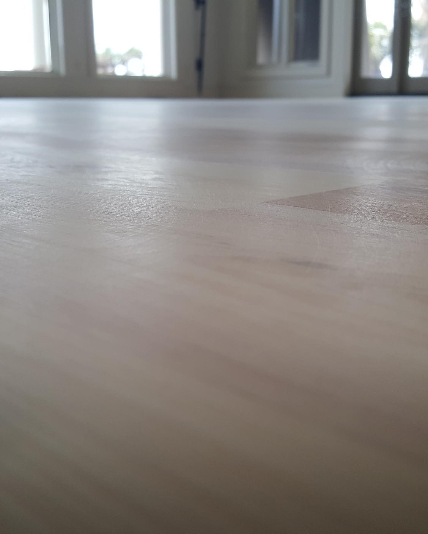 A close up of a wooden table with a window in the background.