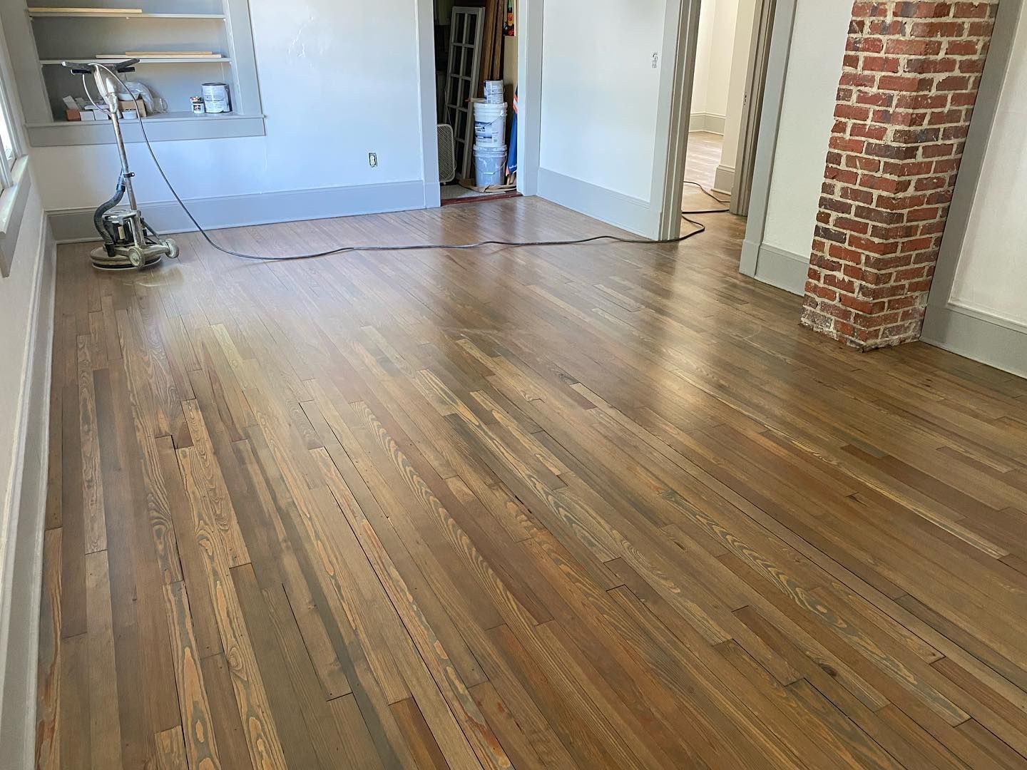A vacuum cleaner is sitting on a wooden floor in a room.