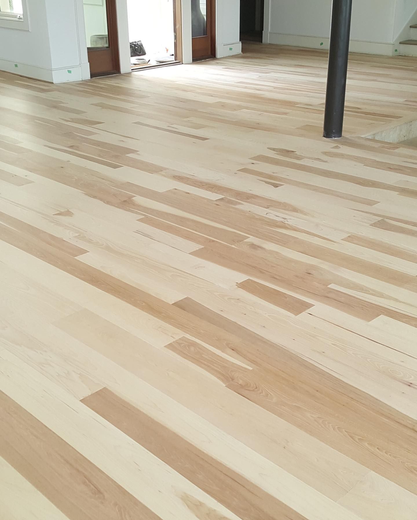 A wooden floor in a room with a door in the background.