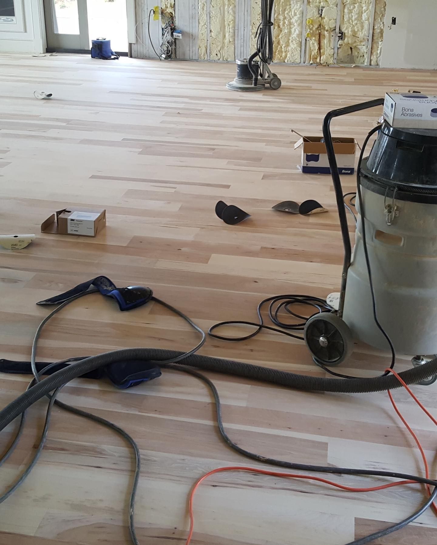 A vacuum cleaner is sitting on a wooden floor in a room.