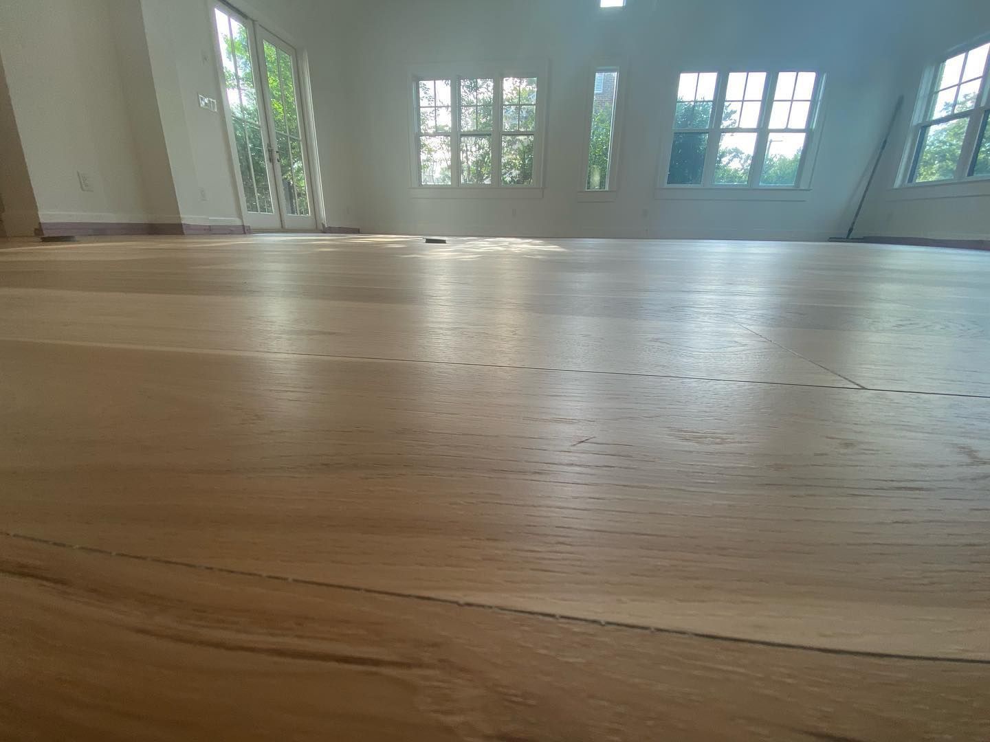 A large empty room with a wooden floor and lots of windows.