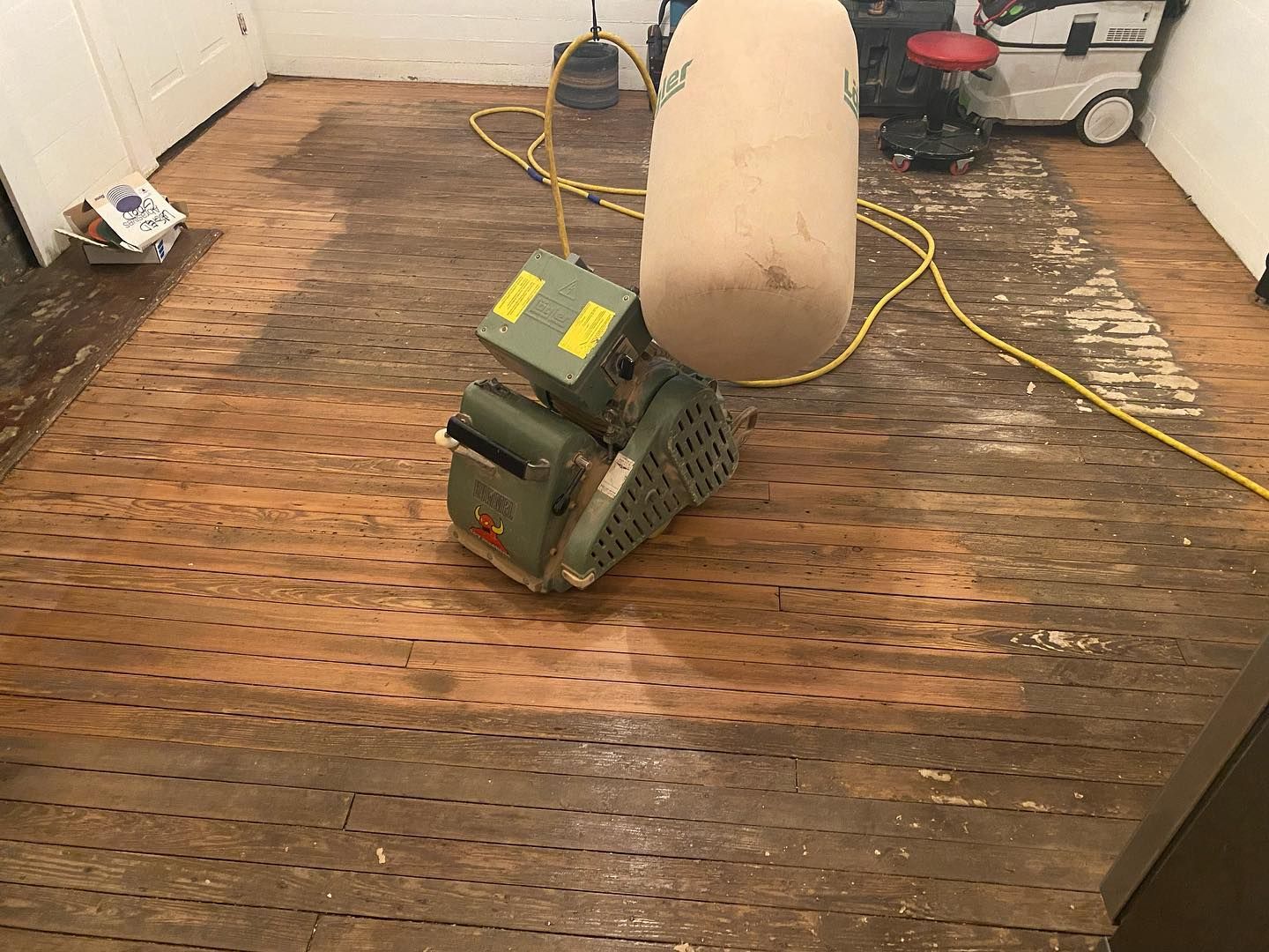A machine is sanding a wooden floor in a room.