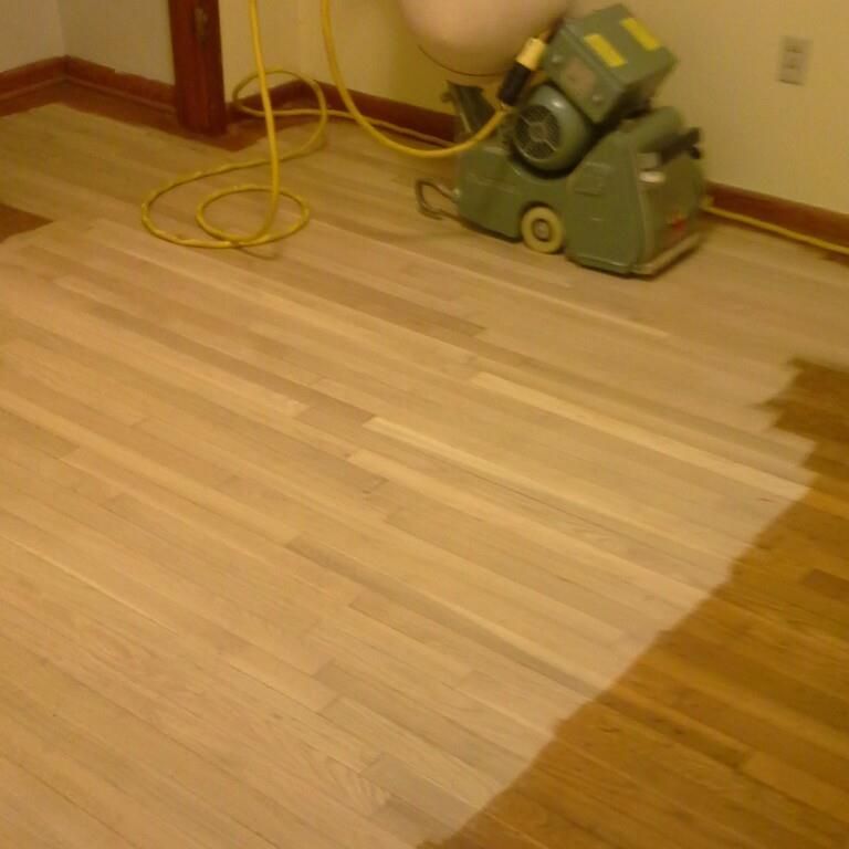A machine is sanding a wooden floor in a room.