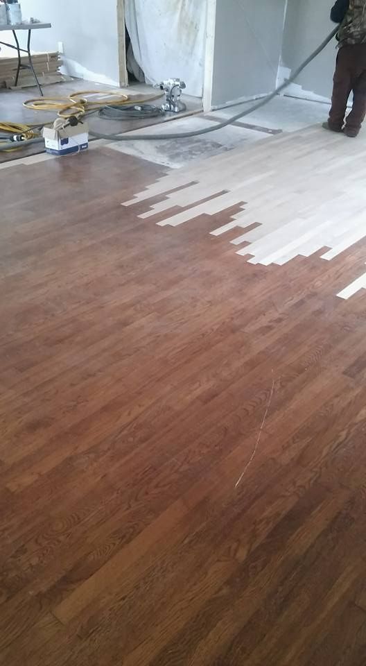 A person is painting a wooden floor with a vacuum cleaner.