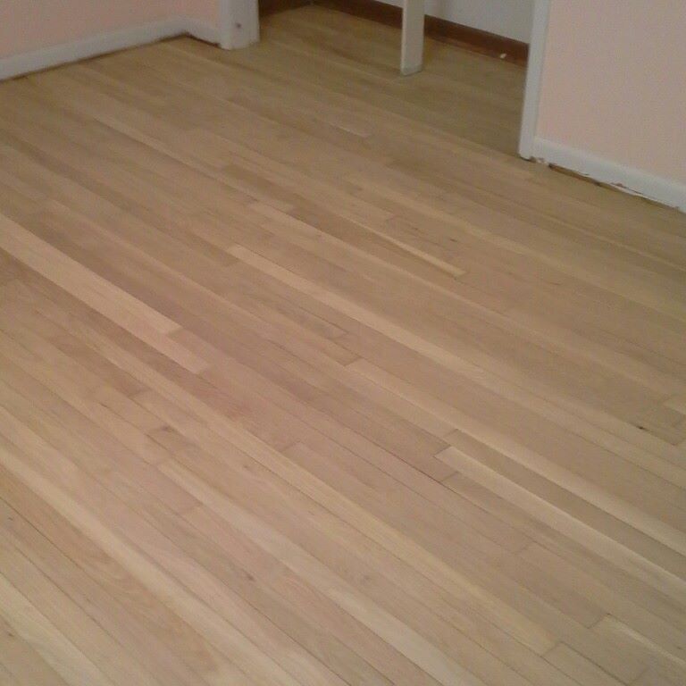A wooden floor in a room with pink walls.