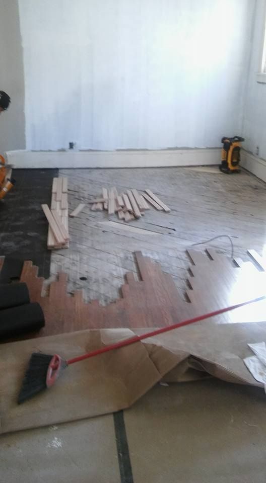 A room with a wooden floor and a broom on the floor.