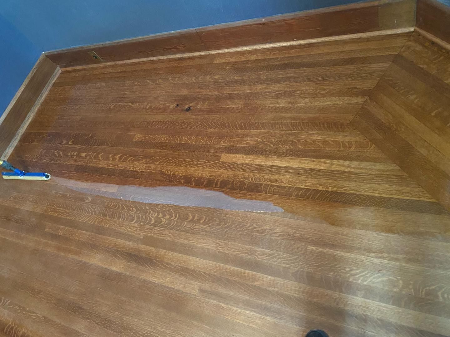 A person is cleaning a wooden floor with a mop.