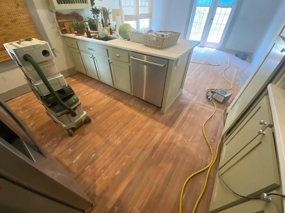 A kitchen with wooden floors and a vacuum cleaner on the floor.