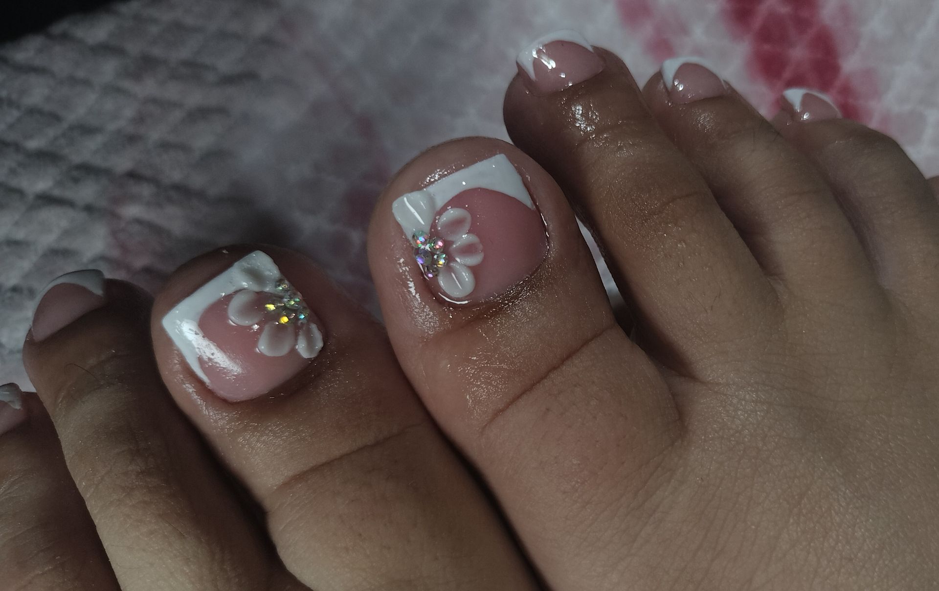 A close up of a woman's toenails with a flower design