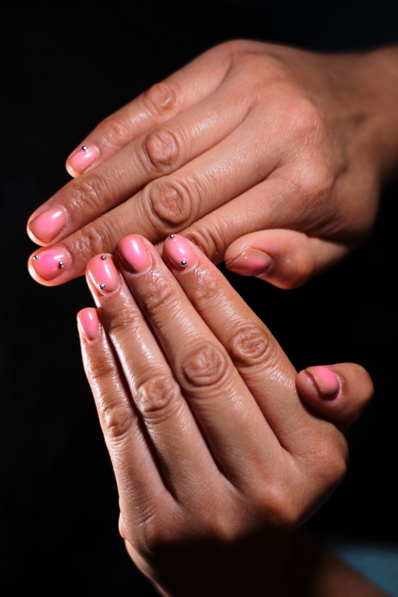 A close up of a woman's hands with pink nails