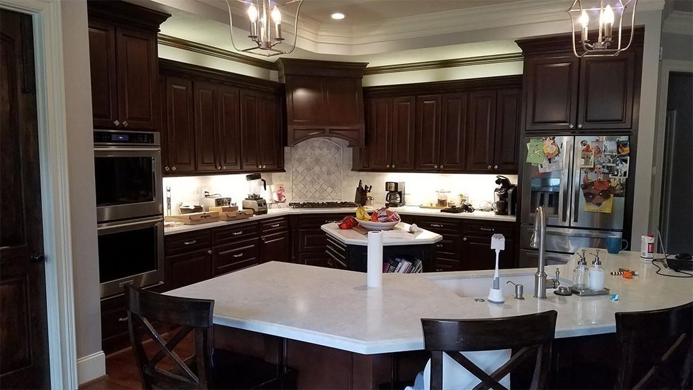 Dark wood kitchen with white countertops and stainless steel appliances.