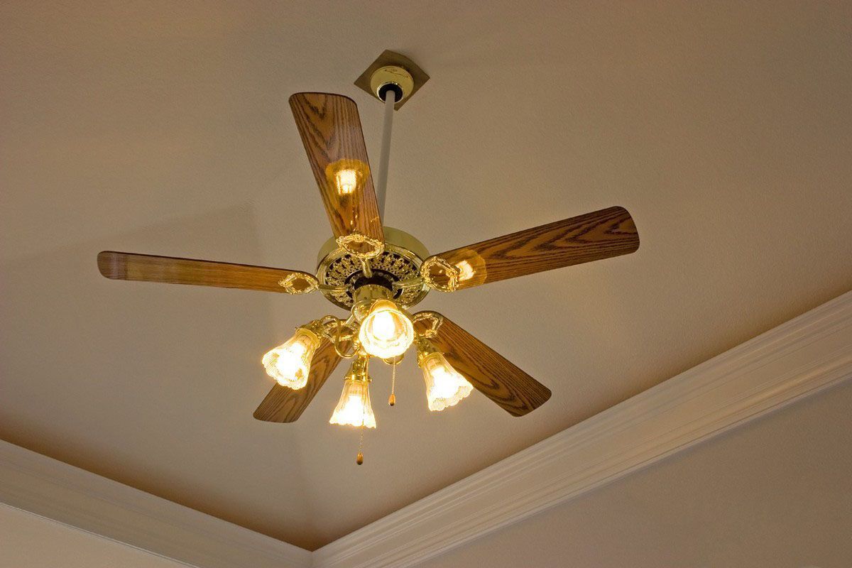 Ceiling fan with five wooden blades and four lights, mounted on a white ceiling.