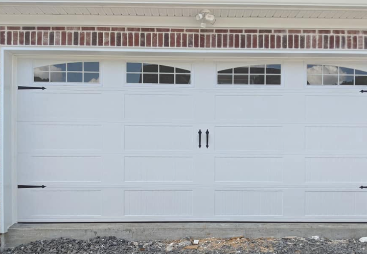 White garage door with small windows along the top, set in a beige house exterior.