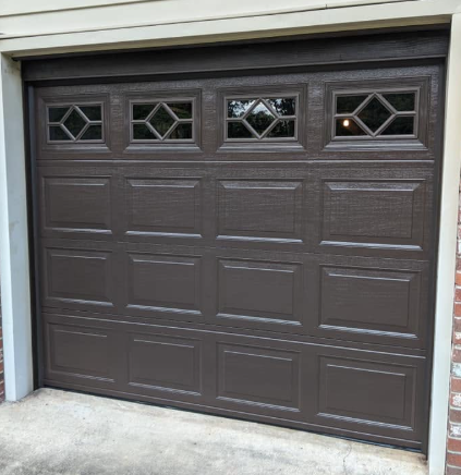 Dark brown garage door with small diamond-pane windows at the top, set in a white exterior wall.