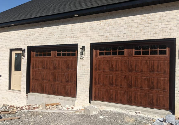 Two brown wooden garage doors on a beige brick house with black trim and a stone driveway
