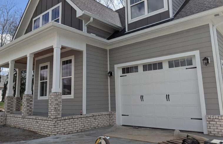 Modern gray house exterior with stone porch and white garage door