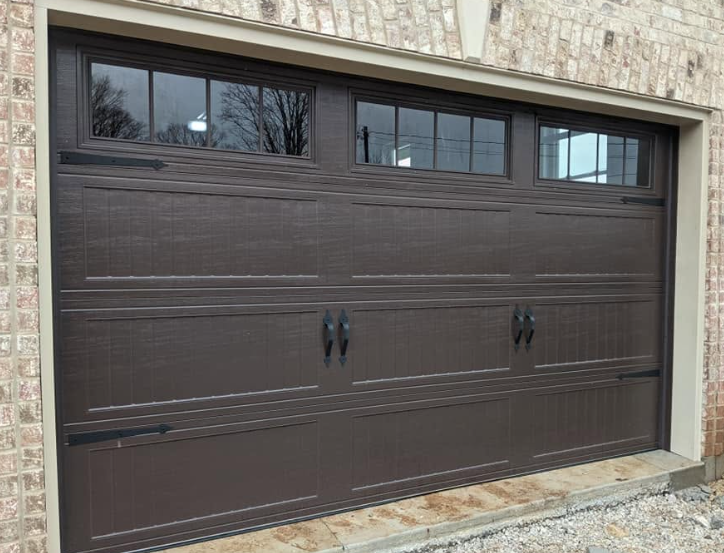 Brown garage door with four small windows, set in a stone exterior wall.