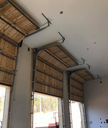 Interior of a construction site with unfinished roll-up doors, exposed framing, and drywall ceiling.