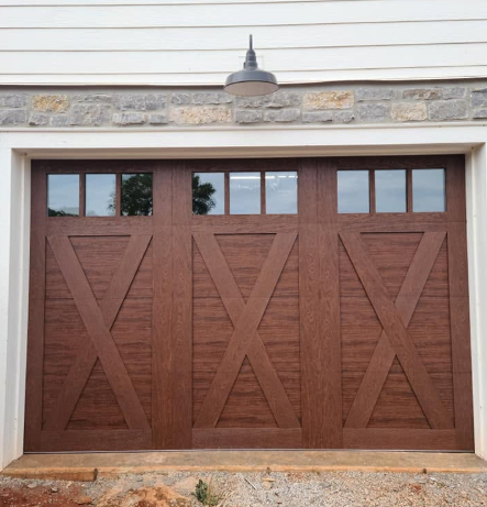Brown wooden three-car garage door with small windows, set in a beige stone and siding exterior