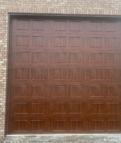 Brown paneled garage door set in a brick exterior wall