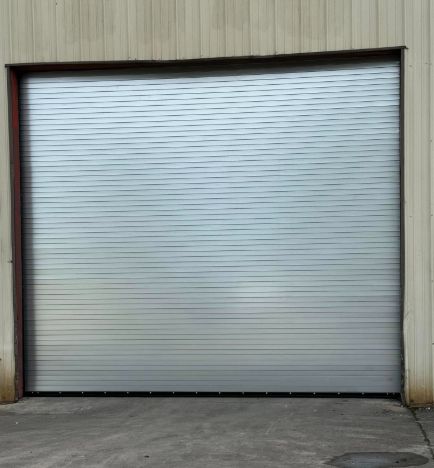 Closed silver roll-up garage door in a beige industrial wall