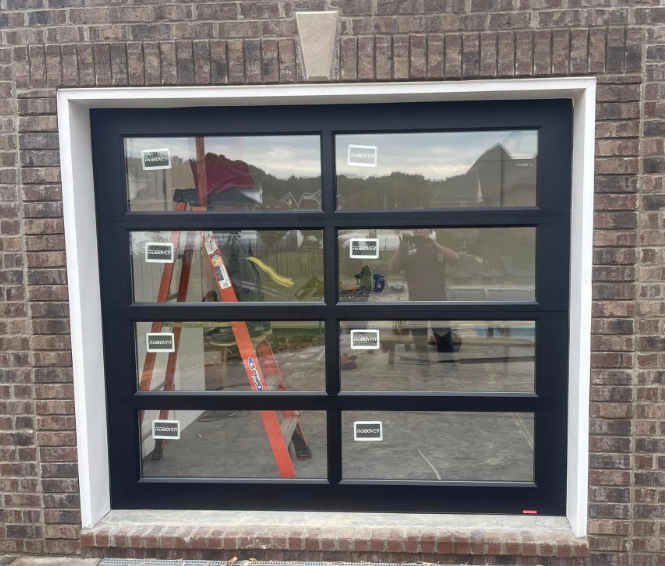 Black-framed garage door with window panes and reflective glass in a brick wall