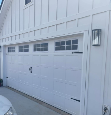 White two-car garage door on a modern house exterior with a wall lantern beside it.