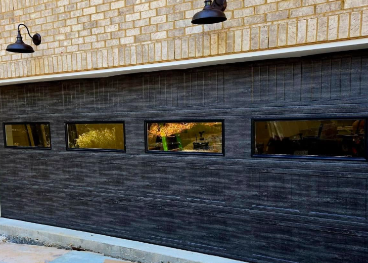 Stone building exterior with four narrow windows, dark lower facade, and two black wall lamps
