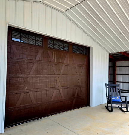 Brown garage door in a white metal building with a concrete floor and a rocking chair nearby