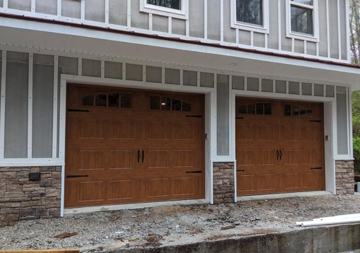 Two wooden garage doors beneath a white-trimmed building exterior with stone lower walls.