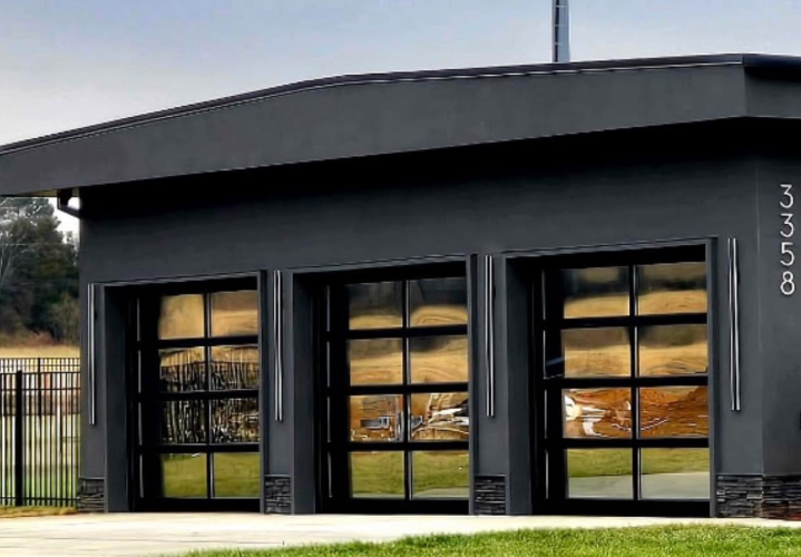 Modern dark gray building with large glass garage-style doors and address 3358 on the facade