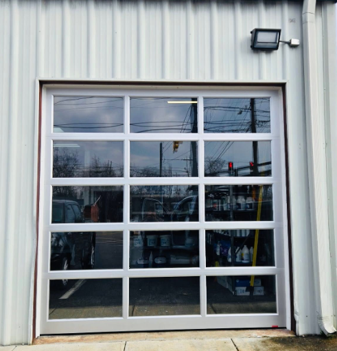 Glass garage door on a corrugated metal building with a wall light above it