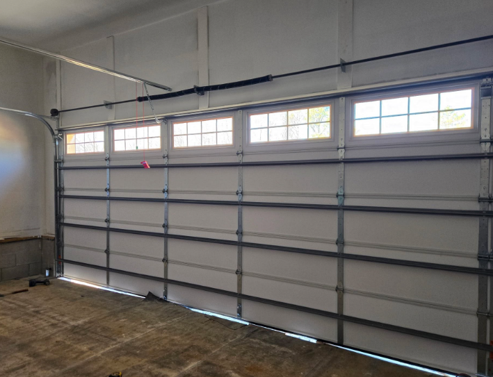 Empty garage interior with a closed white sectional door and small windows along the top.