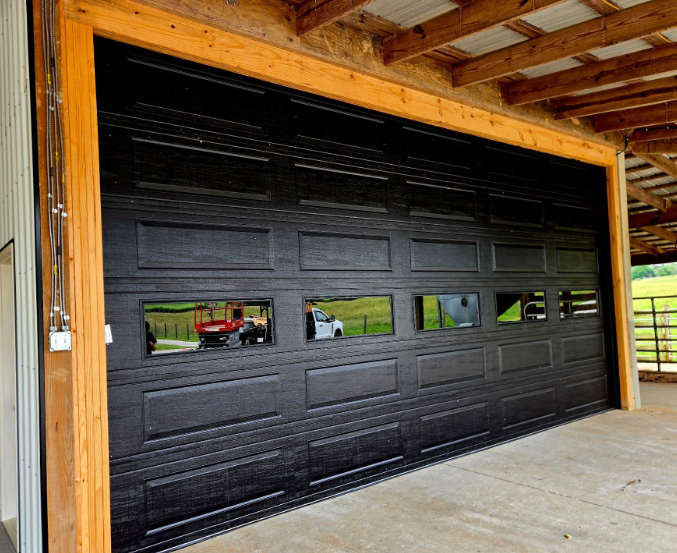 Black sectional garage door with narrow windows in a wooden-framed garage opening