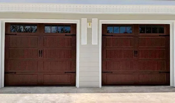 Two brown garage doors on a light beige house facade