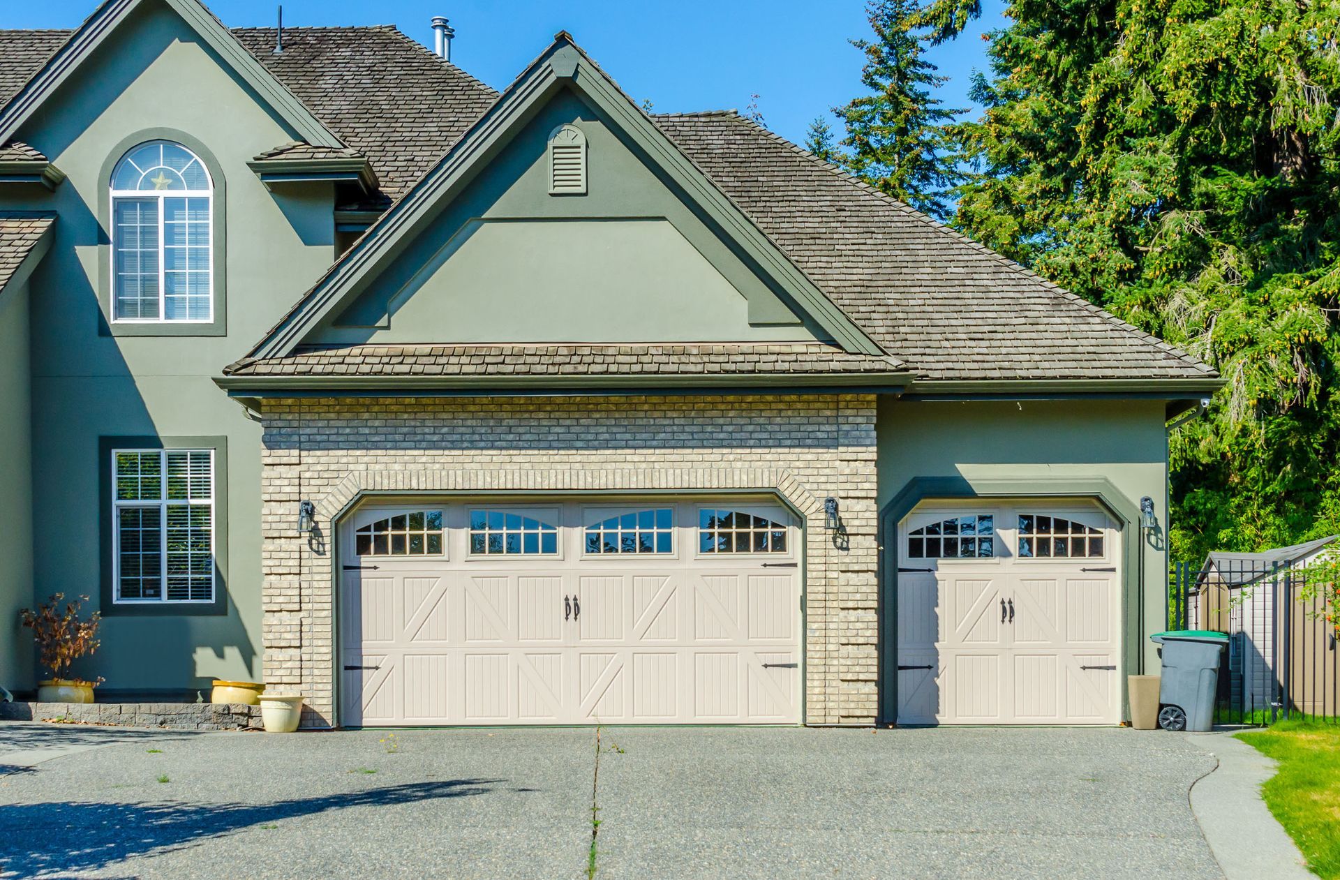 House with a two-car garage, white doors, and a gravel driveway under a clear blue sky