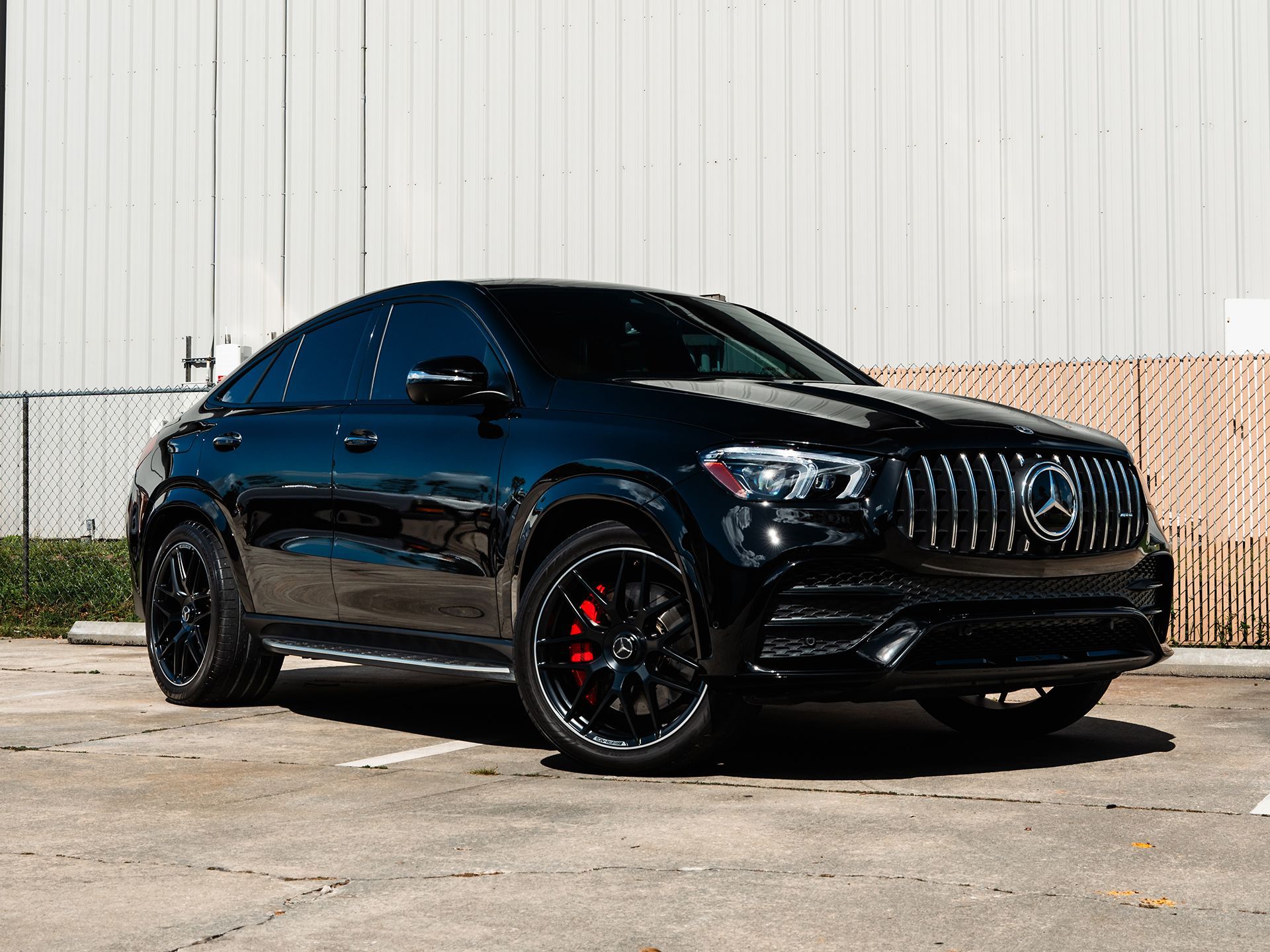 A black Mercedes Benz Gle 63 amg is parked in a parking lot in front of a building.