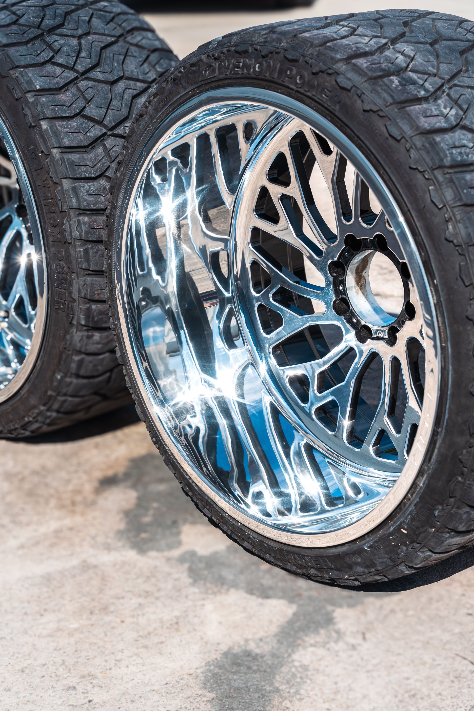 A pair of chrome wheels and tires are sitting on a concrete surface.