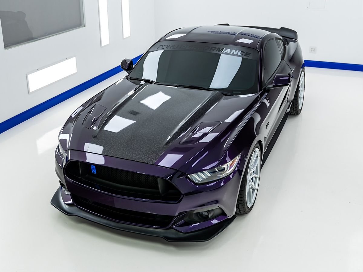 A purple Ford Mustang is parked in a garage.